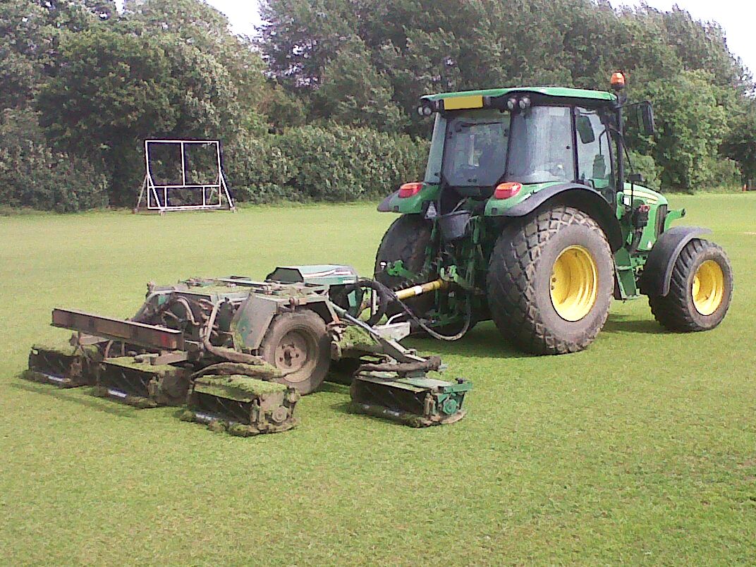 Tractor-trailed cylinder gang mowers cutting a playing field