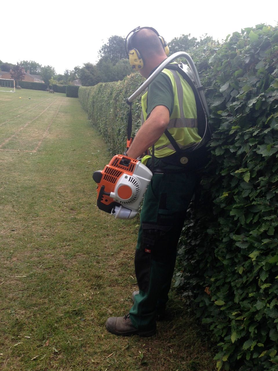 Green Scythe operative cutting a hedge